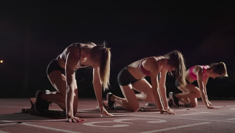 Slow-motion-3-female-runners-running-to-the-camera-in-a-sports-arena.-Track-and-field-athletics-competition-running-in-the-dark.-Race-together